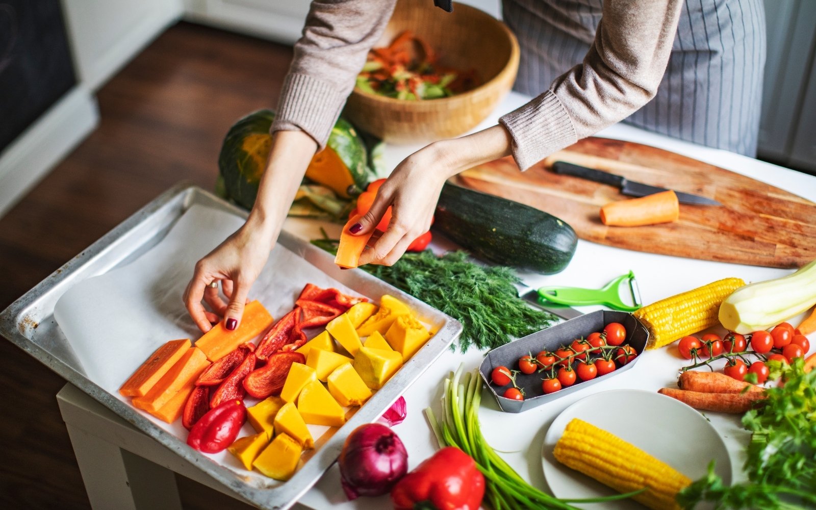 Person placing cut vegetables on baking sheet