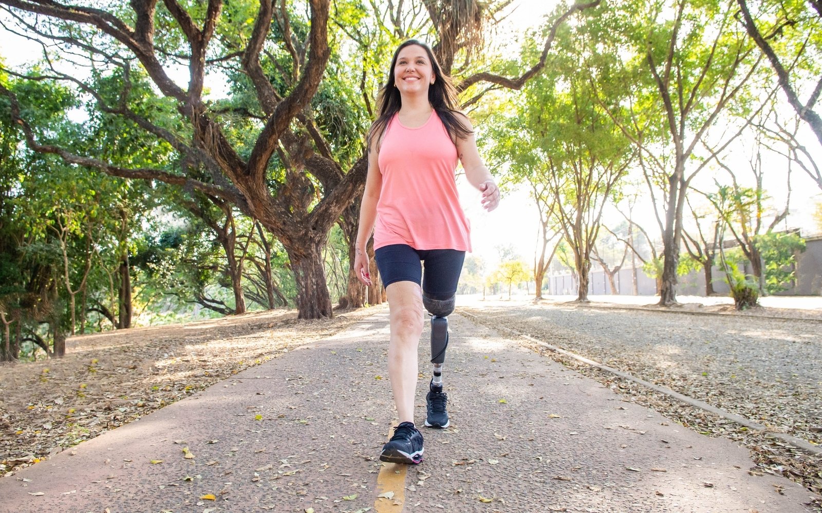 Woman with prosthetic leg smiling on nature walk